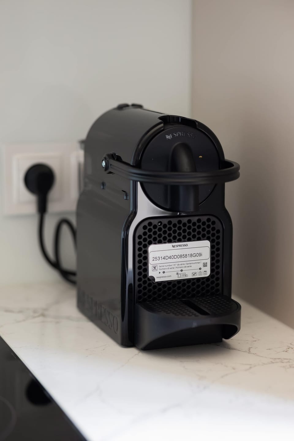 A compact coffee station with a capsule coffee machine placed on a clean countertop. The setup is practical and convenient for preparing a quick cup of coffee.