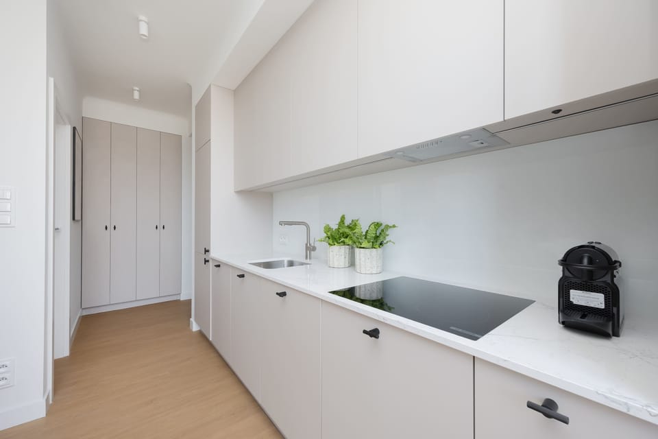 Another view of the kitchenette highlights the long countertop and functional storage space. The minimalist design ensures both convenience and visual harmony.