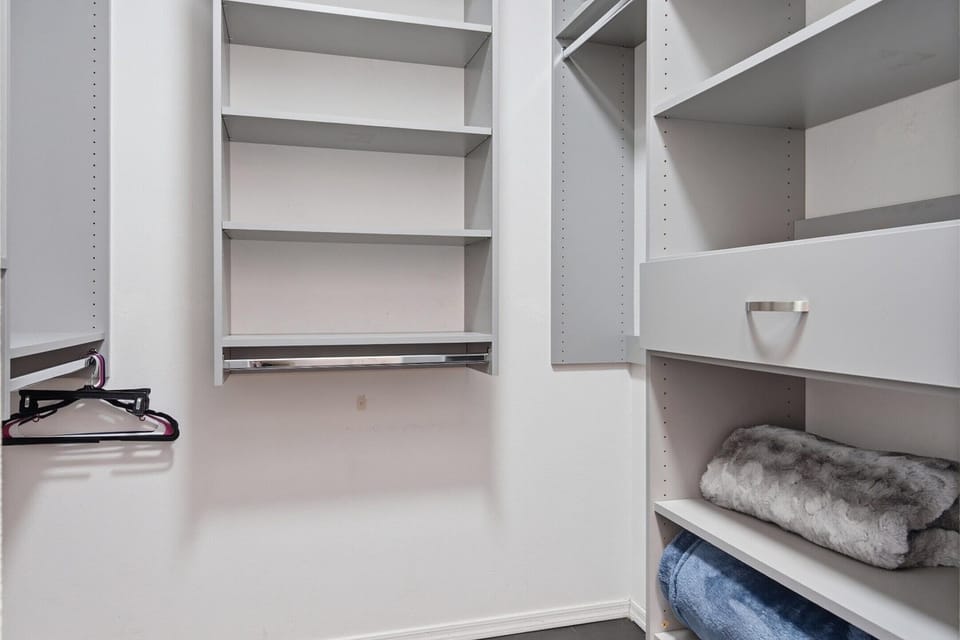 Primary Bedroom featuring a King bed, smart TV, walk-in closet, access to the private balcony, and an en-suite bathroom.