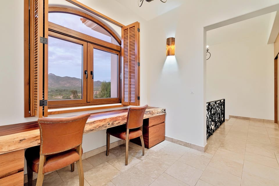 Settle into your private workspace with sweeping mountain views through beautiful arched windows, where warm leather seating meets rustic wood details.