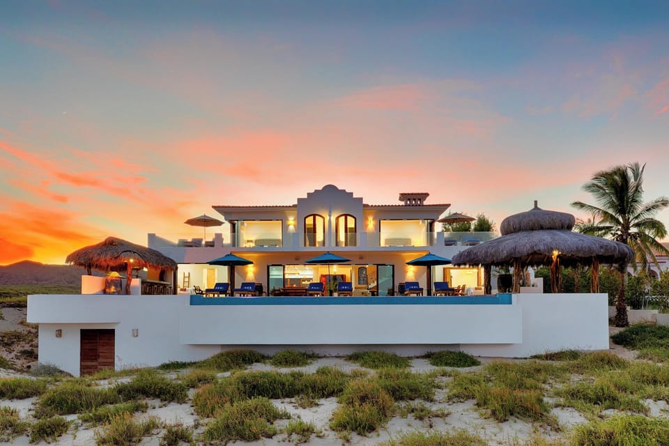 Stunning beachfront villa with infinity pool captures dramatic sunset views over pristine coastline and tropical landscape.