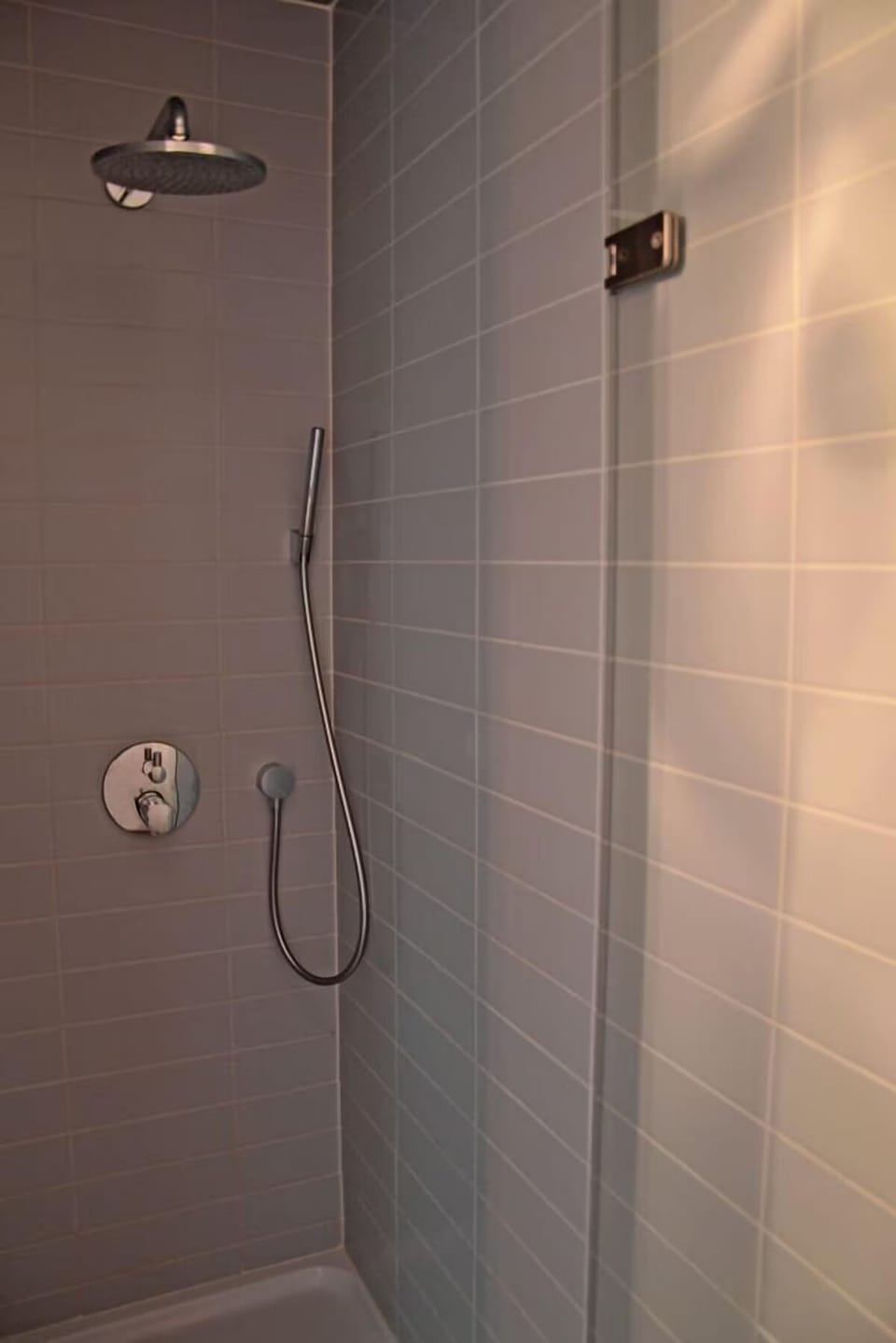 Rinse off under a rainfall shower in a sleek space.