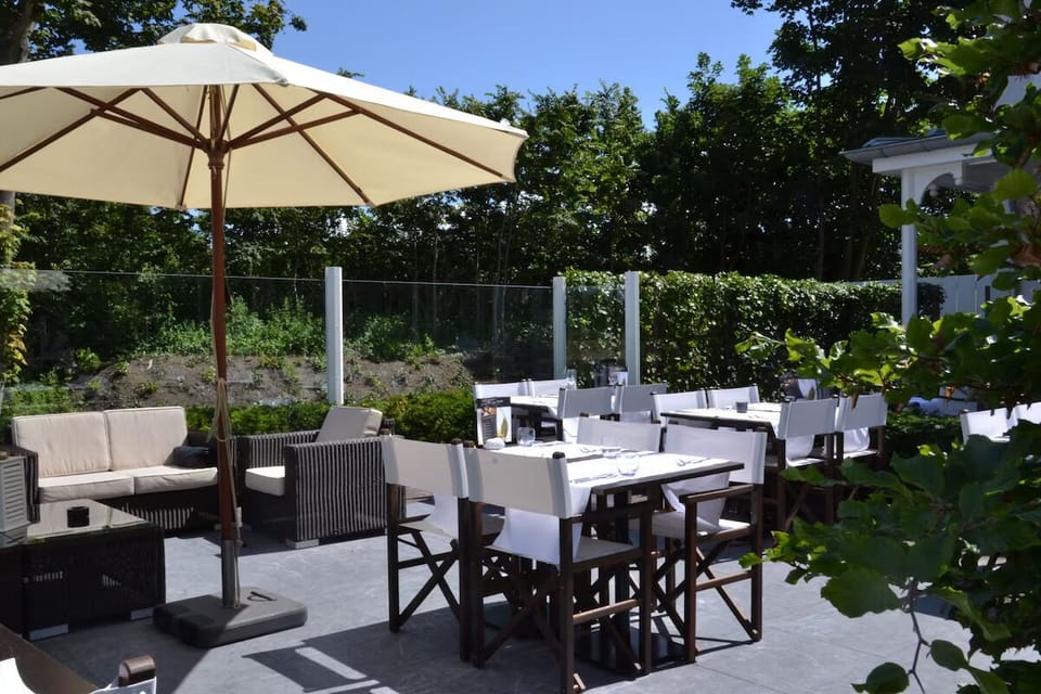 Dine alfresco in the sun with umbrellas and garden views.