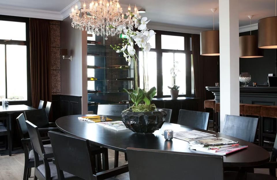 Gather for elegant meals beneath chandeliers in a moody setting.