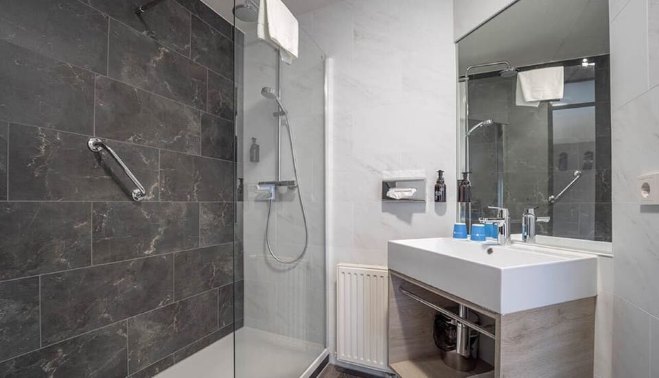 Refresh under a sleek walk-in shower with modern finishes.