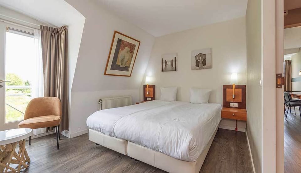 Wake refreshed in crisp linens beside a sunlit window.