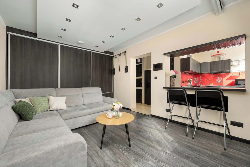 A functional breakfast bar is paired with high-backed black chairs, offering a view into the kitchen's red-tiled workspace.