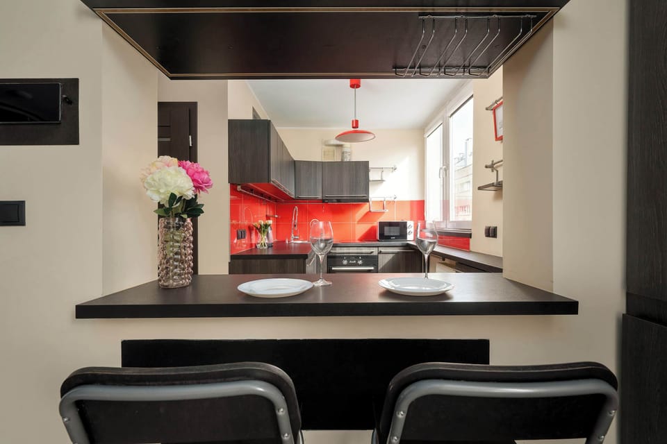 A view from the breakfast bar overlooks the kitchen area, highlighting the sleek countertops and the red accent wall.