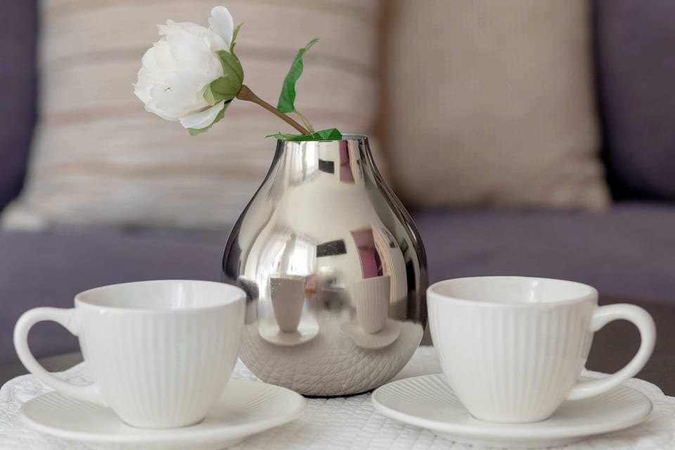 A tea set with two cups and a small vase on a tray. Cozy detail emphasizing homey touches.