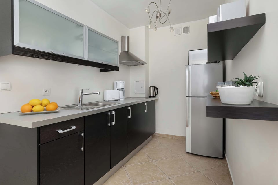A modern kitchen with black and white cabinets and a sink area. Oranges on the counter provide a pop of color.
