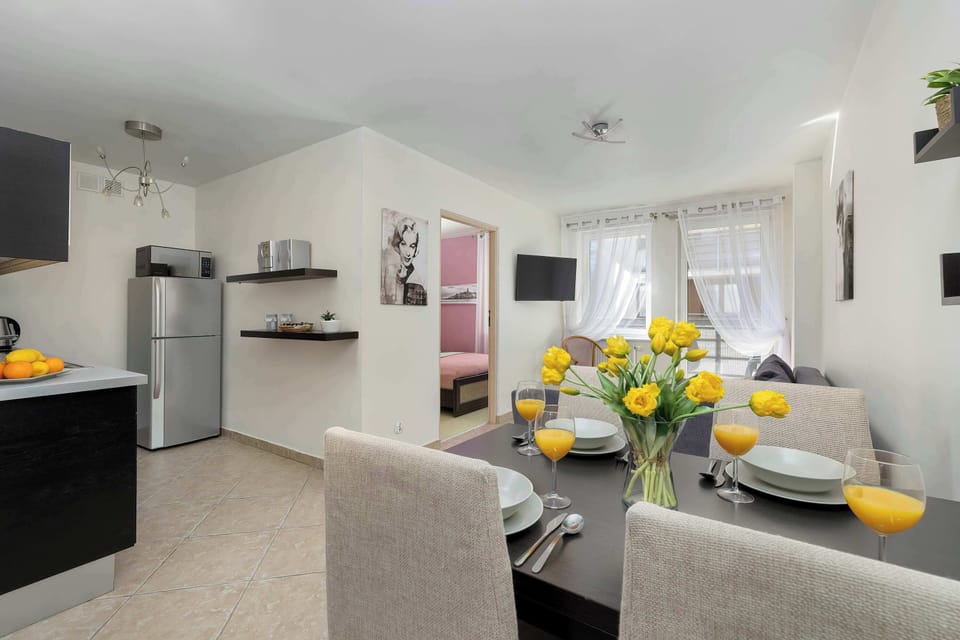 A dining and living area featuring a table with chairs and a sofa. Fresh flowers on the table add a welcoming touch.