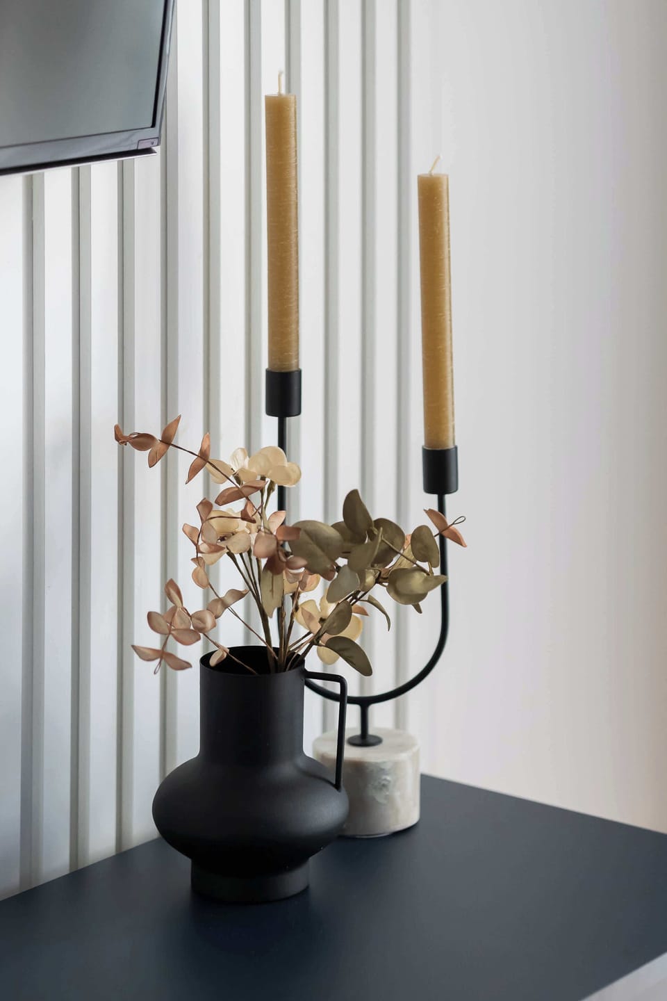 Decorative candles and flowers arranged on a dark table.
