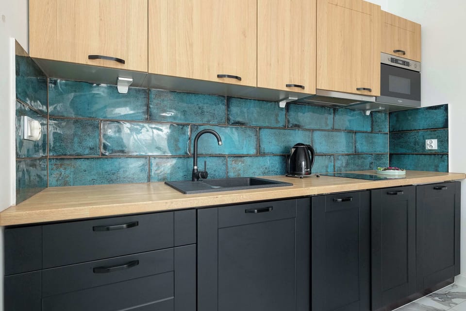 The kitchen workspace is well-organized with a black sink and modern appliances against the vibrant tile wall.