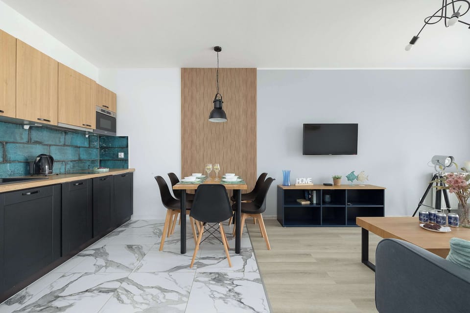 The kitchenette area features striking turquoise backsplash tiles, black cabinetry, and a wooden countertop.