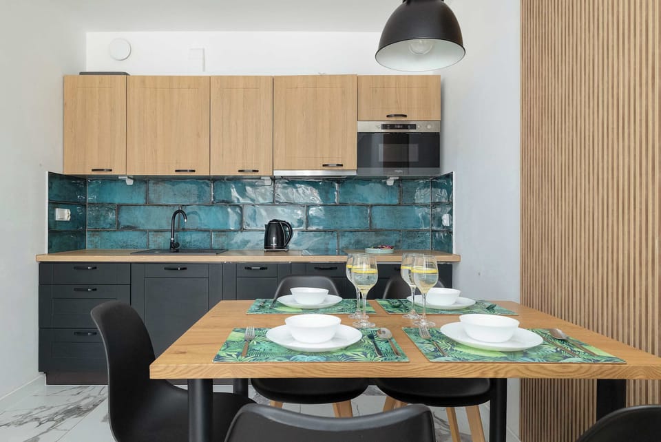 A focused shot of the dining table shows the modern chairs and the seamless integration with the kitchen.