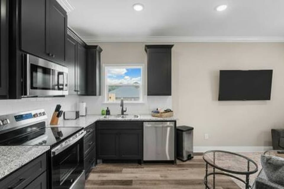 Whip up delicious meals in this modern, spacious kitchen featuring sleek black cabinetry, granite countertops, and stainless steel appliances. Perfect for families and couples!