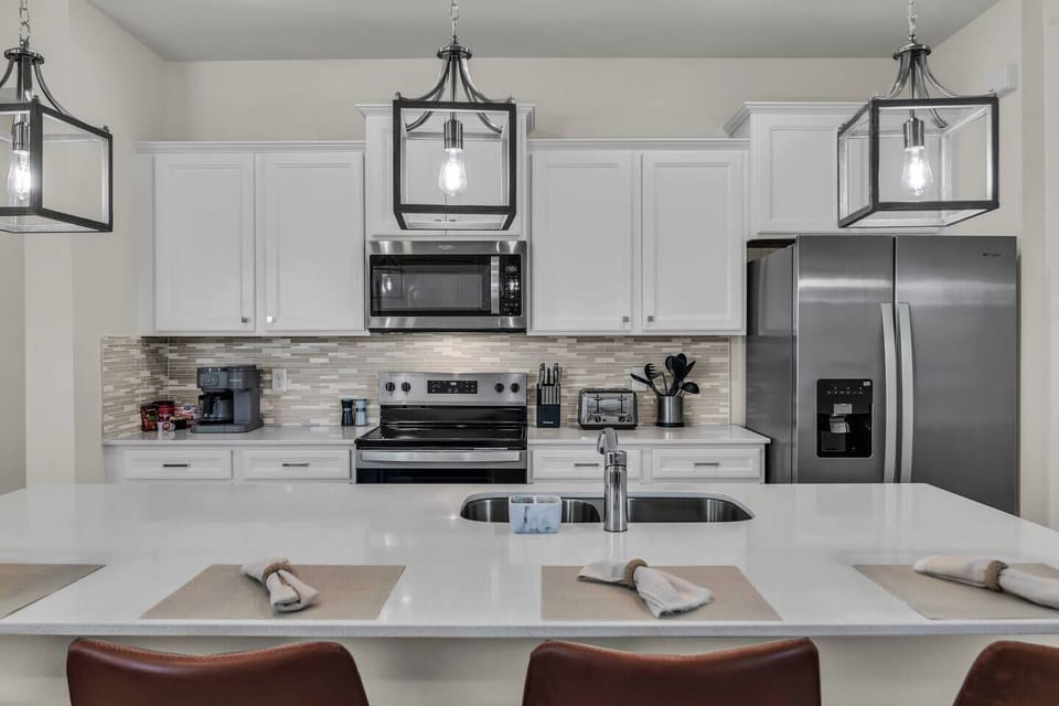 Modern kitchen w/ sleek stainless appliances & crisp white cabinetry.