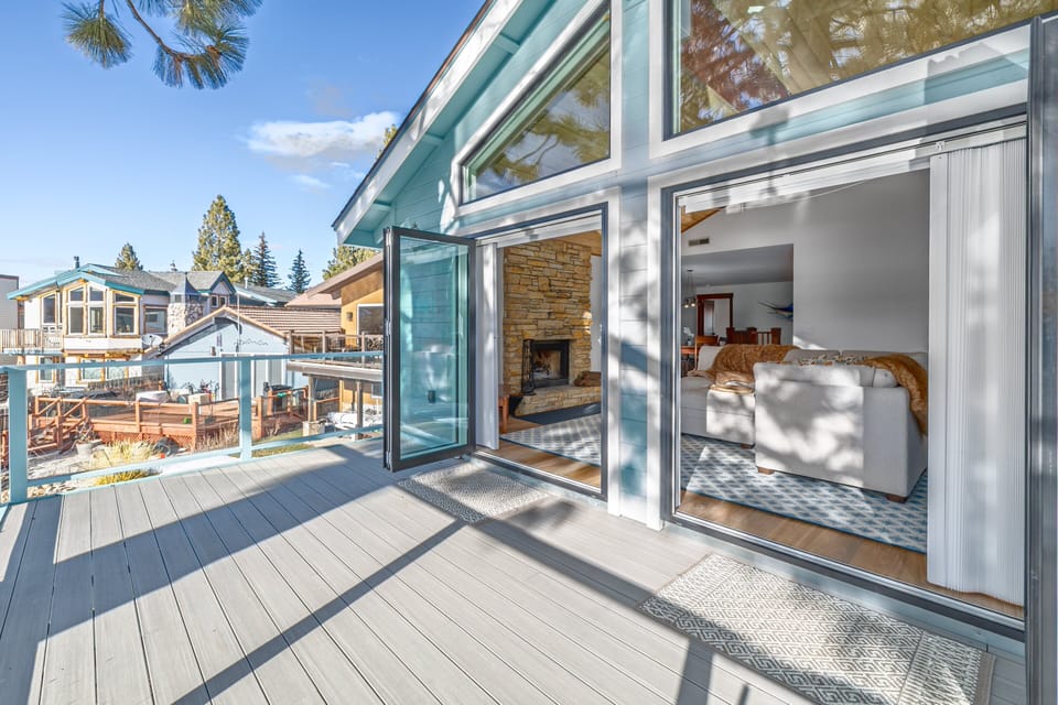 Deck with railing, sliding doors, indoor fireplace in view, canal view, and sunlit outdoor space.