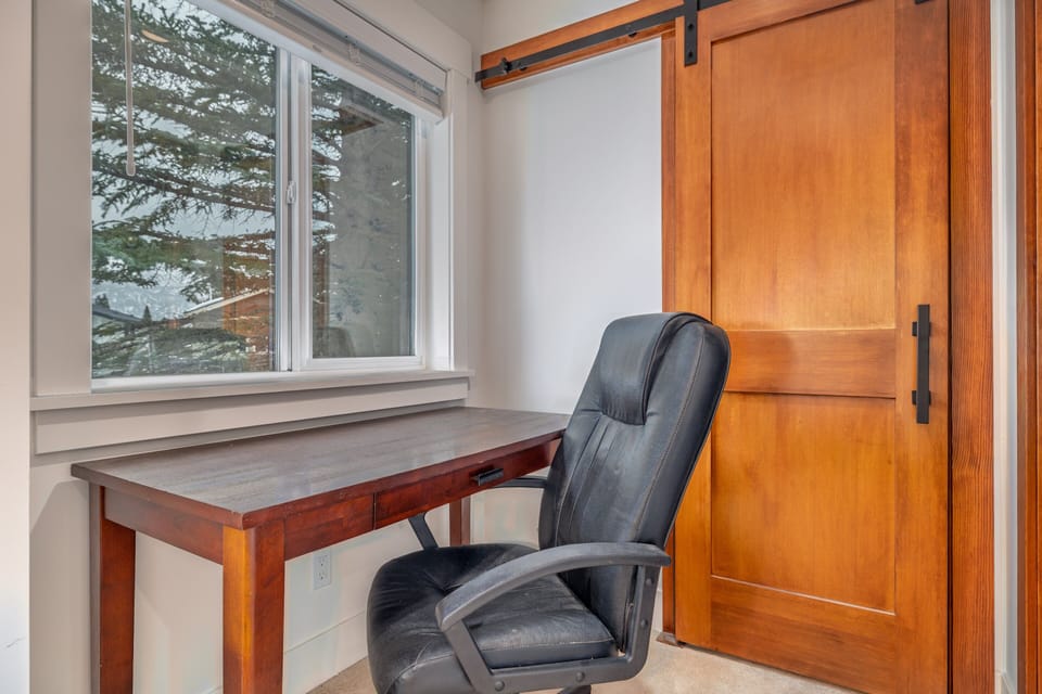 Office nook with desk, chair, window, and closet door for a quiet laptop spot.