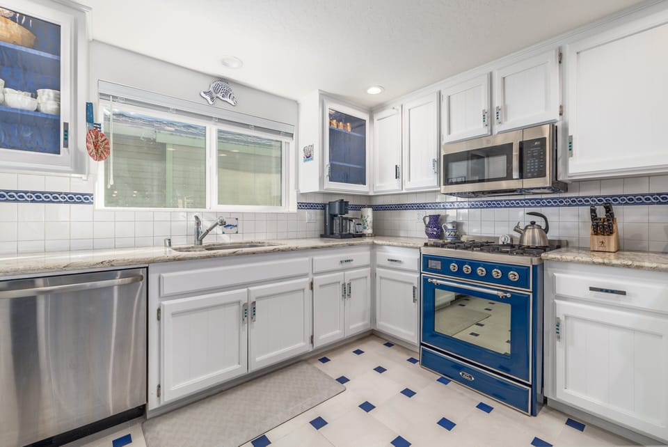 Kitchen with sink, dishwasher, range, microwave, refrigerator, coffee maker, window, and prep space.