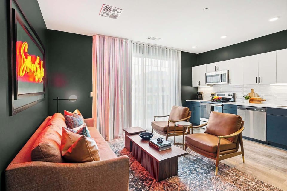 Bright and open living area featuring a smart TV, plush furnishings, and access to the private balcony. Connects to the dining area and kitchen.