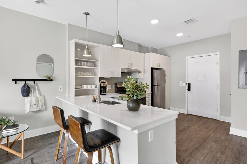 Kitchen island with sleek white waterfall island with two dark leather barstools.