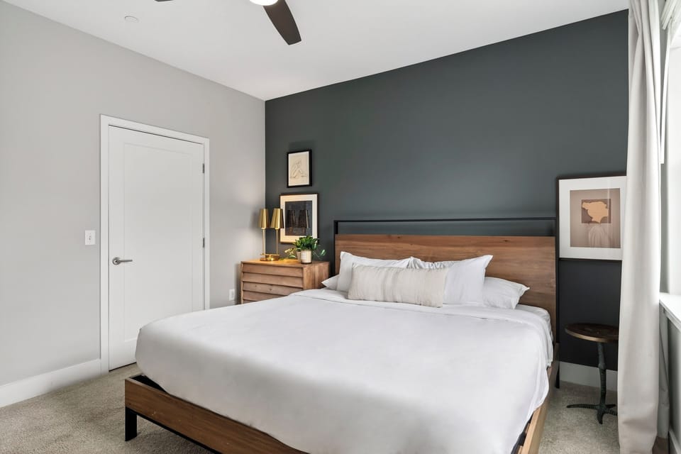 King-sized bed with a wood headboard against a dark grey accent wall.