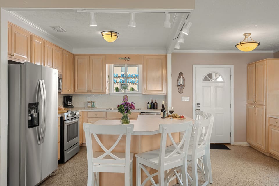 Bright modern kitchen with light wood cabinetry, stainless steel appliances, and a welcoming island set for wine and bites.