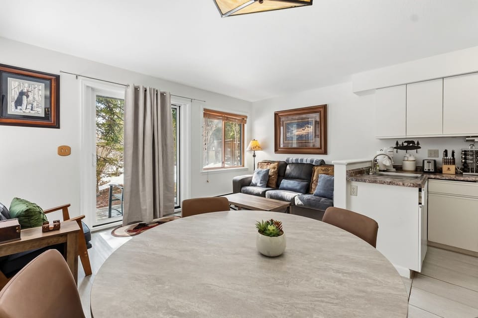 Your stylish open-concept space blends dining and living areas seamlessly, with modern amenities and peaceful nature views through large windows.