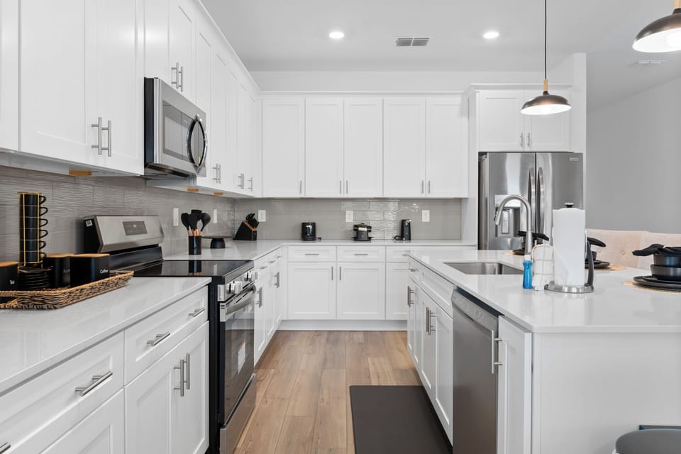 Step into your modern culinary haven with sleek white cabinets, granite counters, and stainless appliances ready for your next meal creation.