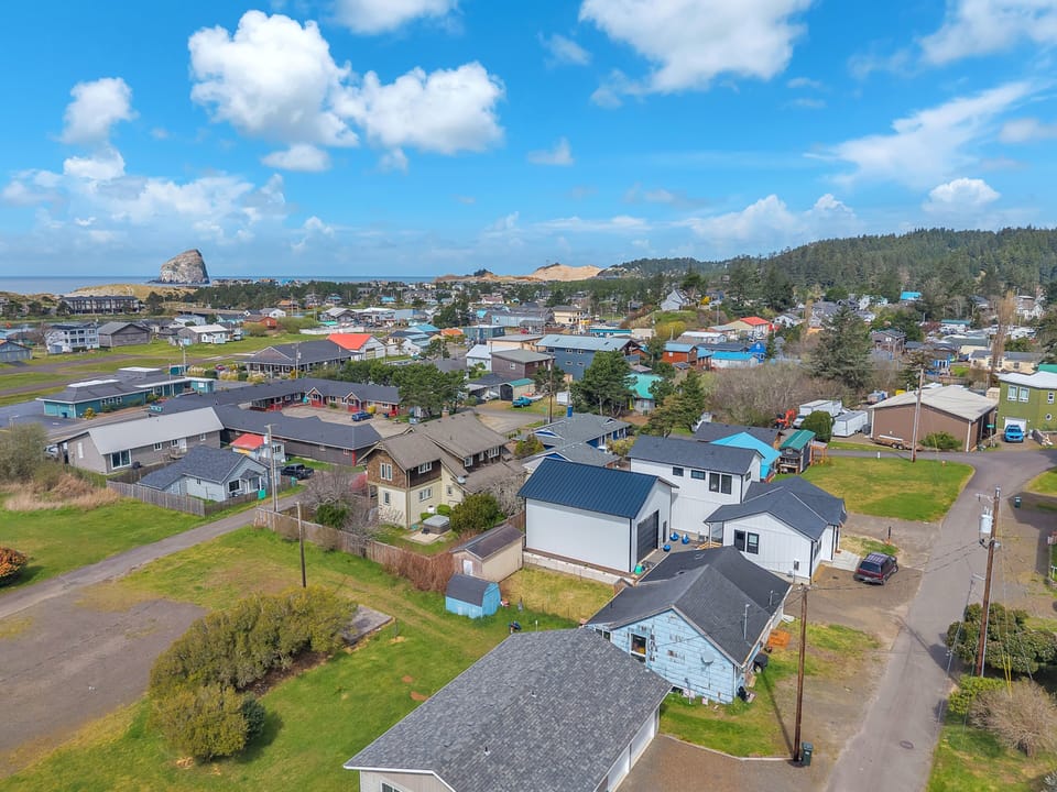 Charming coastal community nestled between forested hills and ocean, featuring colorful homes and peaceful residential streets.