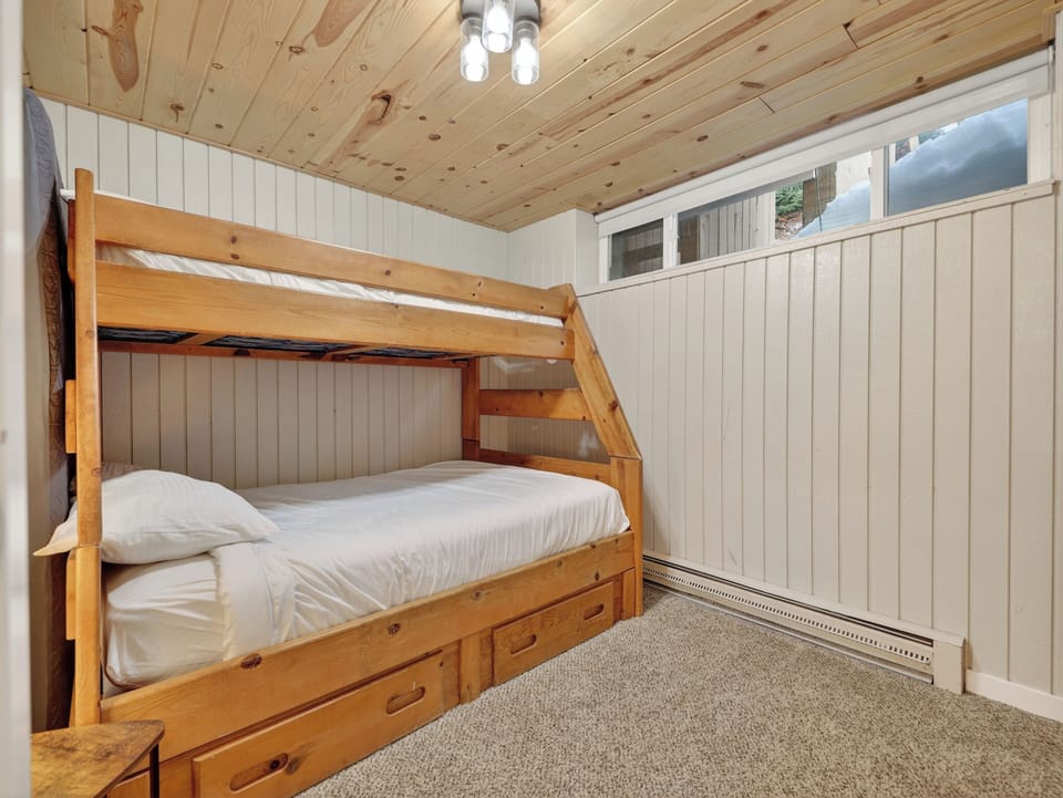 Cozy wood-paneled bedroom with built-in bunk bed and storage drawers - perfect for your family getaway adventures.