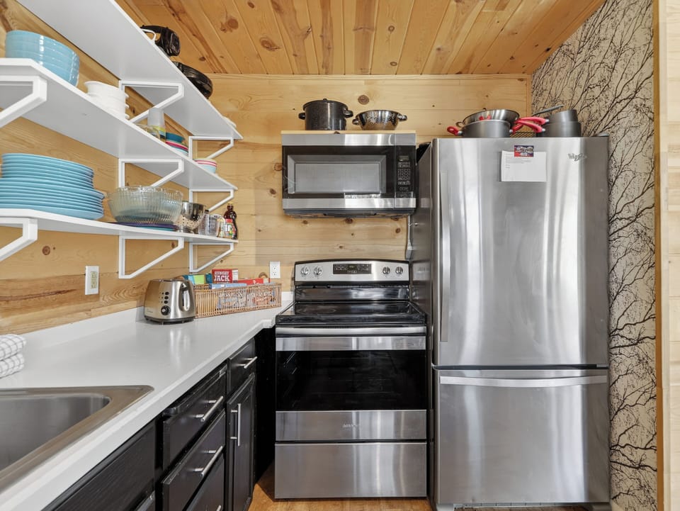 Your cozy mountain kitchen has everything you need—stainless steel appliances, open shelving, and warm wood finishes for memorable meal prep.