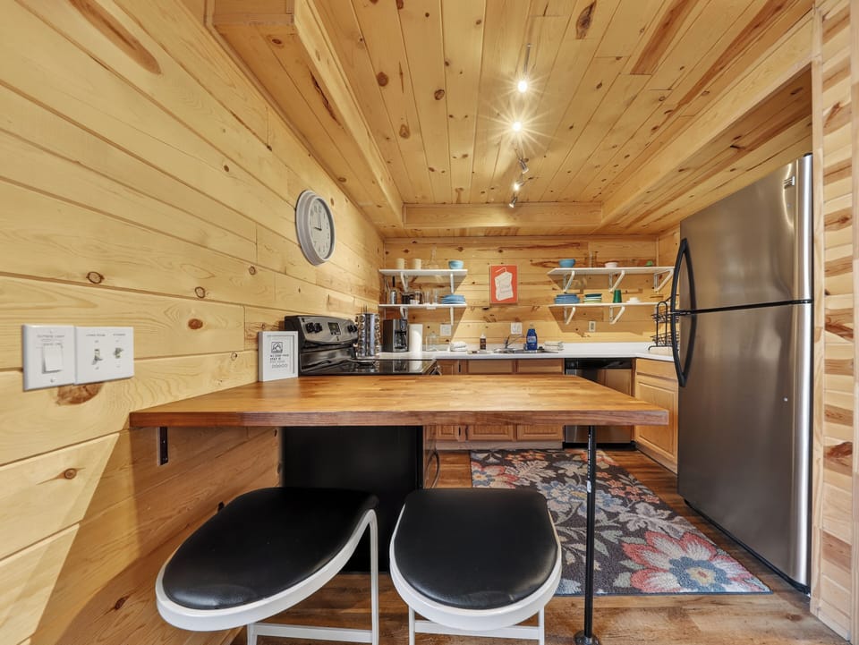 Your rustic kitchen features warm wood walls, modern appliances, and a cozy breakfast bar where you'll enjoy morning coffee.
