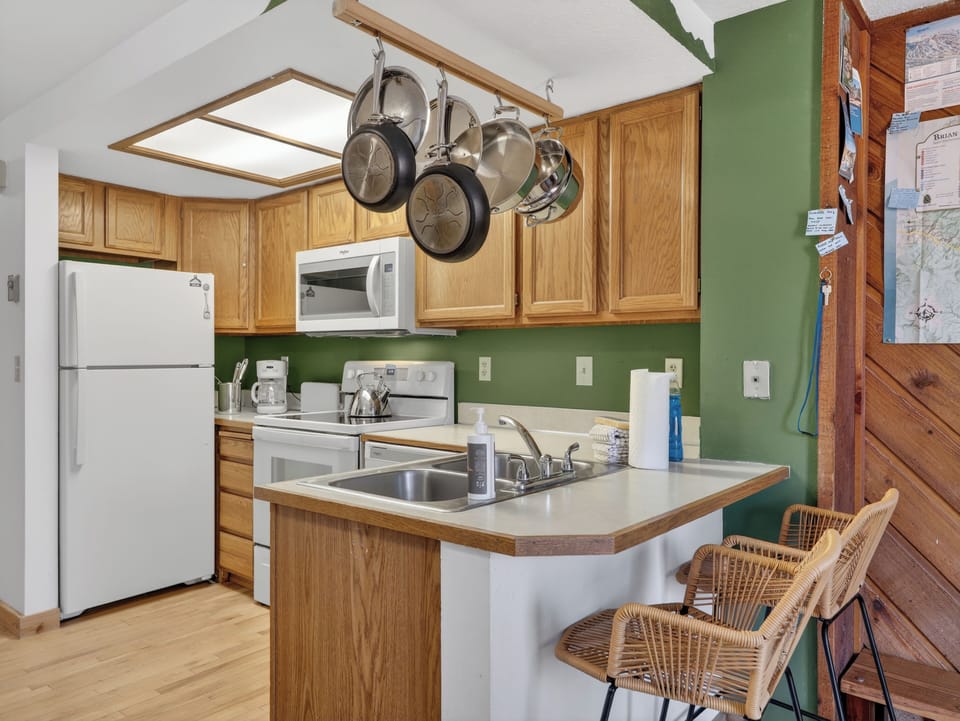 Your fully equipped kitchen features warm wood cabinets, modern appliances, and a breakfast bar perfect for morning coffee or casual meals.