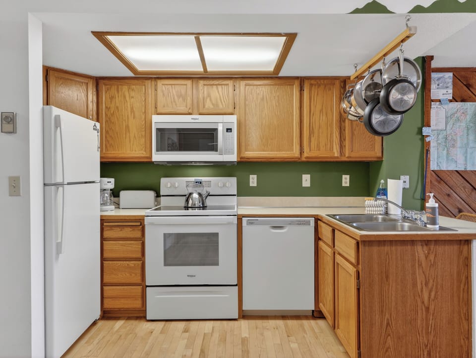Cook your favorite meals in this fully-equipped kitchen with warm oak cabinets, modern appliances, and cheerful green accents.