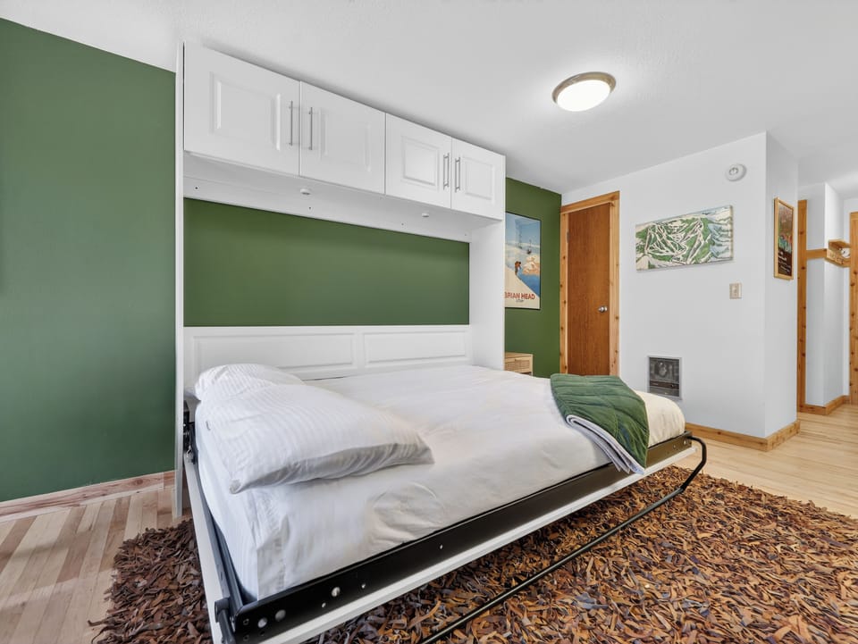 Your clever murphy bed maximizes space while providing cozy comfort with cheerful green accents and thoughtful built-in storage above.