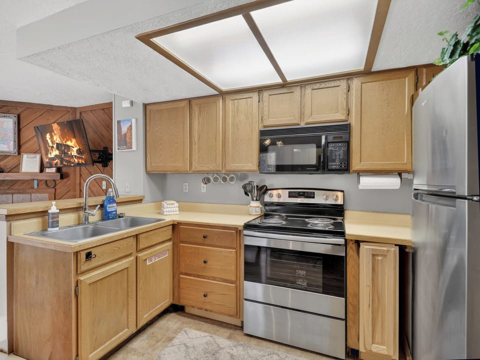 Your fully-equipped kitchen features warm wood cabinets, stainless appliances, and a cozy fireplace view for memorable meal prep.