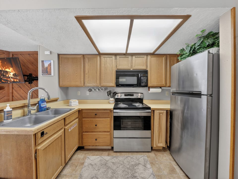 Your fully equipped kitchen features warm wood cabinetry, stainless steel appliances, and a bright skylight overhead for cooking memorable meals.