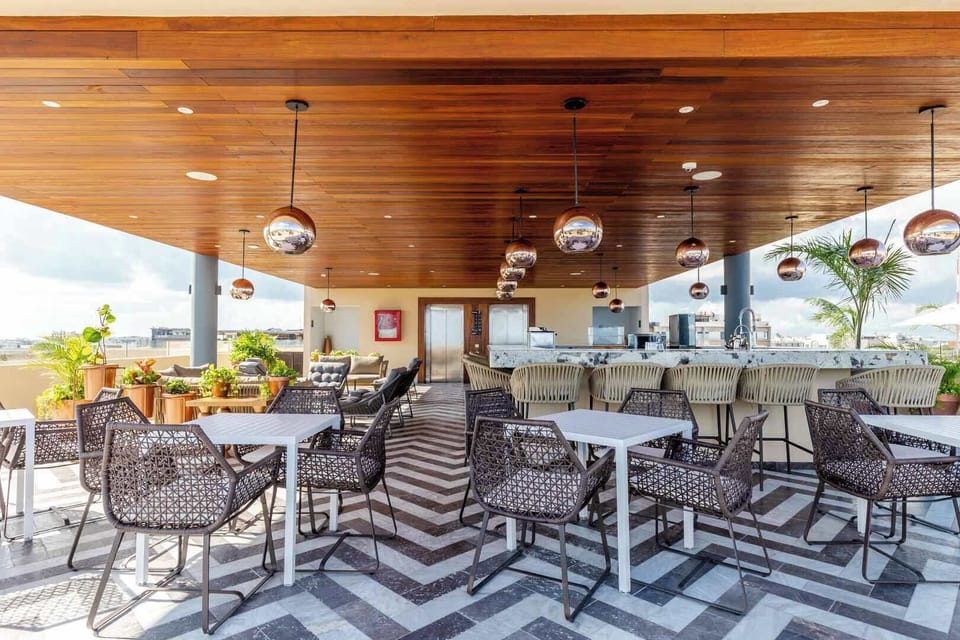 Rooftop lounge and dining area under a warm wood ceiling, an inviting spot to gather over meals just steps from Fifth Avenue in Playa del Carmen