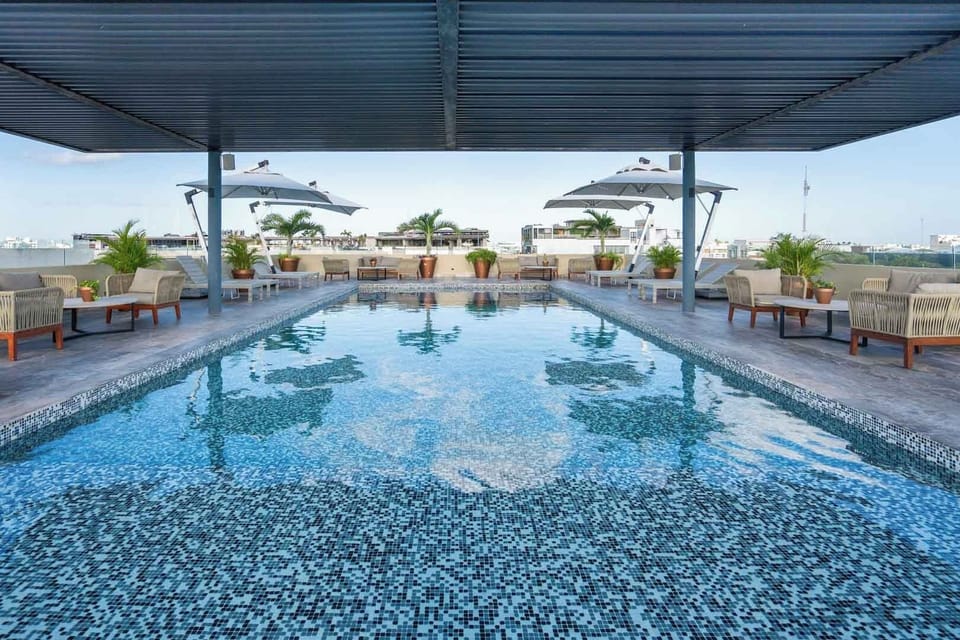 Crystal blue tiled pool framed by umbrellas, an inviting rooftop escape after exploring Fifth Avenue