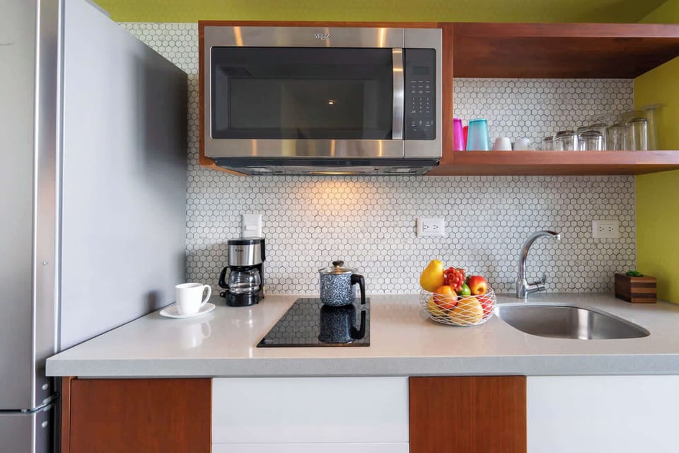 Compact modern kitchenette with cooktop, sink and fresh touches, simple and ready for home-cooked meals