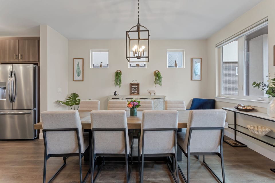 Gather around this elegant dining table where memorable meals unfold under warm pendant lighting, with modern kitchen conveniences just steps away.