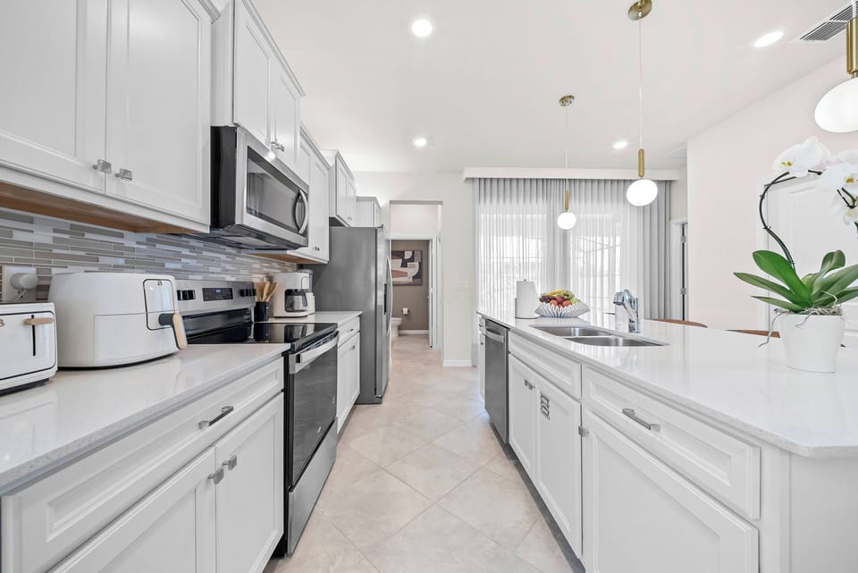 Welcome to this stylish kitchen with sleek white cabinetry and modern stainless steel appliances. Natural light brightens the elegant countertops, creating a warm atmosphere ideal for cooking and gathering with friends and family.