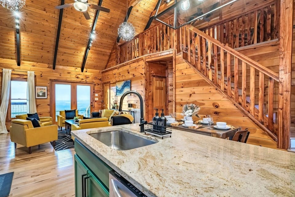 Rustic yet modern open-concept cabin interior featuring kitchen, living, and dining spaces, designed for comfort, socializing, and scenic mountain escapes.