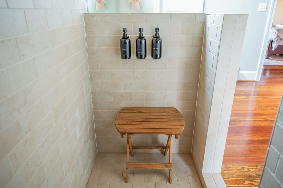 Spa Retreat: Enjoy a refreshing shower with luxury bath products and a chic wooden seating area!