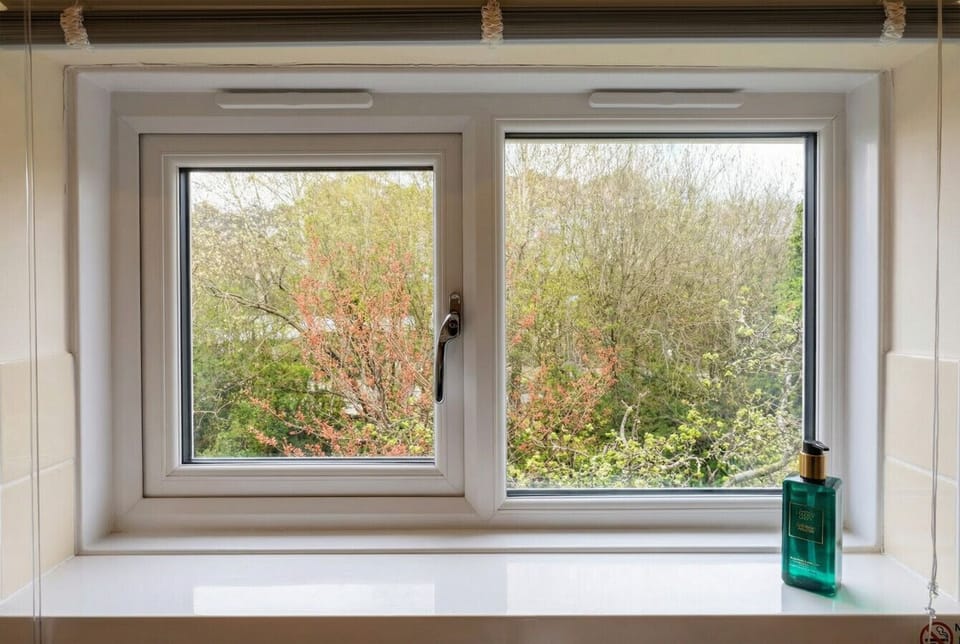The bathroom window frames a peaceful green garden view that feels surprisingly private and calm.