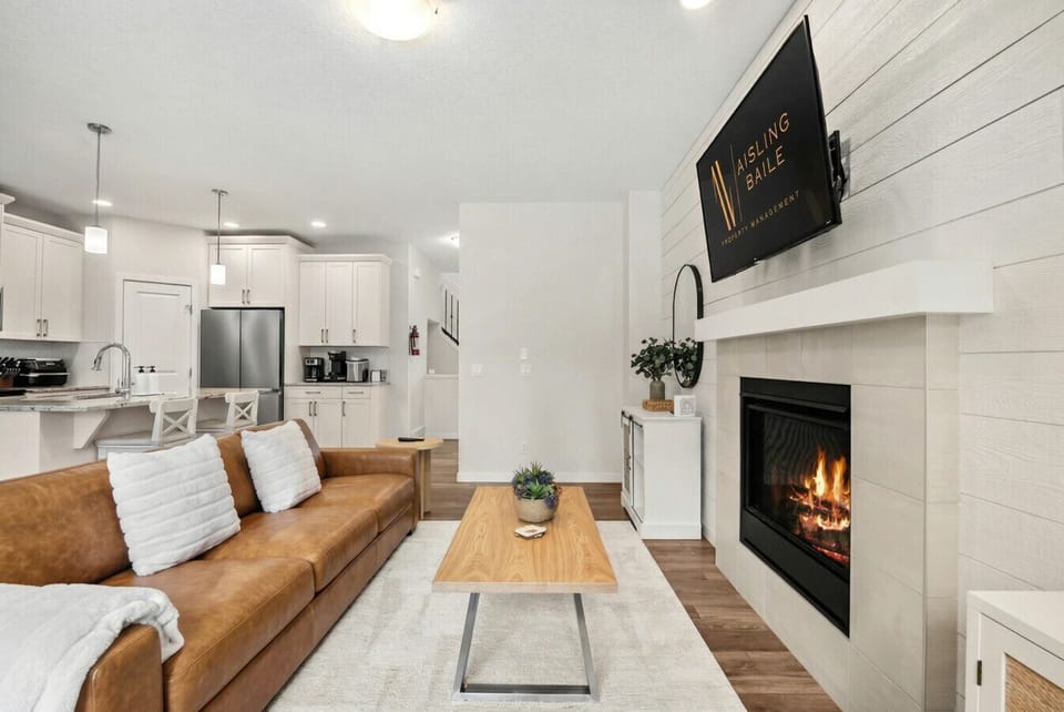 Main floor living room with a 50` Smart TV with cable, gas-lit fireplace, board games, cozy seating options and walkout access to the backyard.