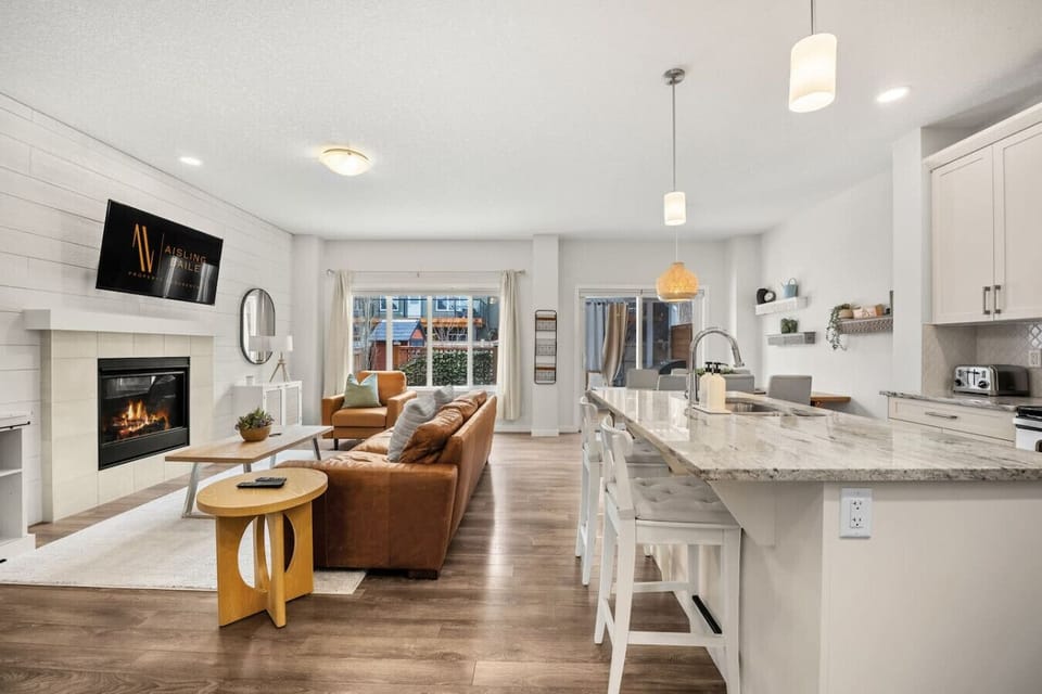 Main floor living room with a 50` Smart TV with cable, gas-lit fireplace, board games, cozy seating options and walkout access to the backyard.