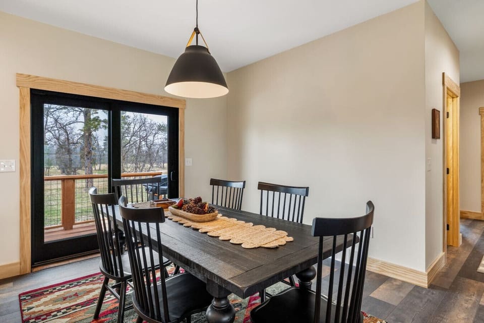 Dine in comfort at a contemporary table set beside large glass doors, offering natural light and views of the outdoors.